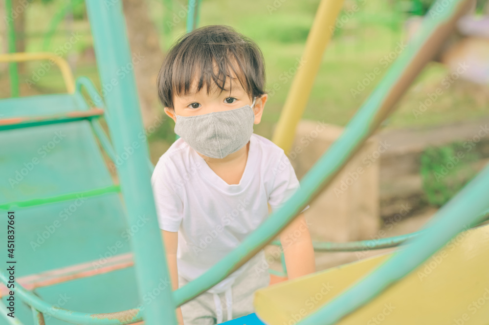 Little boy playing in the playground, the child is wearing a protective mask on the face during the quarantine of coronavirus, covid-19, virus protection. Little boy playing in the playground, the child is wearing a protective mask on the face during the quarantine of coronavirus, covid-19, virus protection.
