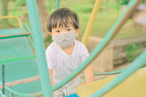 Little boy playing in the playground, the child is wearing a protective mask on the face during the quarantine of coronavirus, covid-19, virus protection.