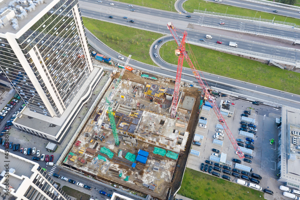 Naklejka premium Aerial top view large-scale construction of a residential complex with a view of construction cranes and road on the outskirts of the city.