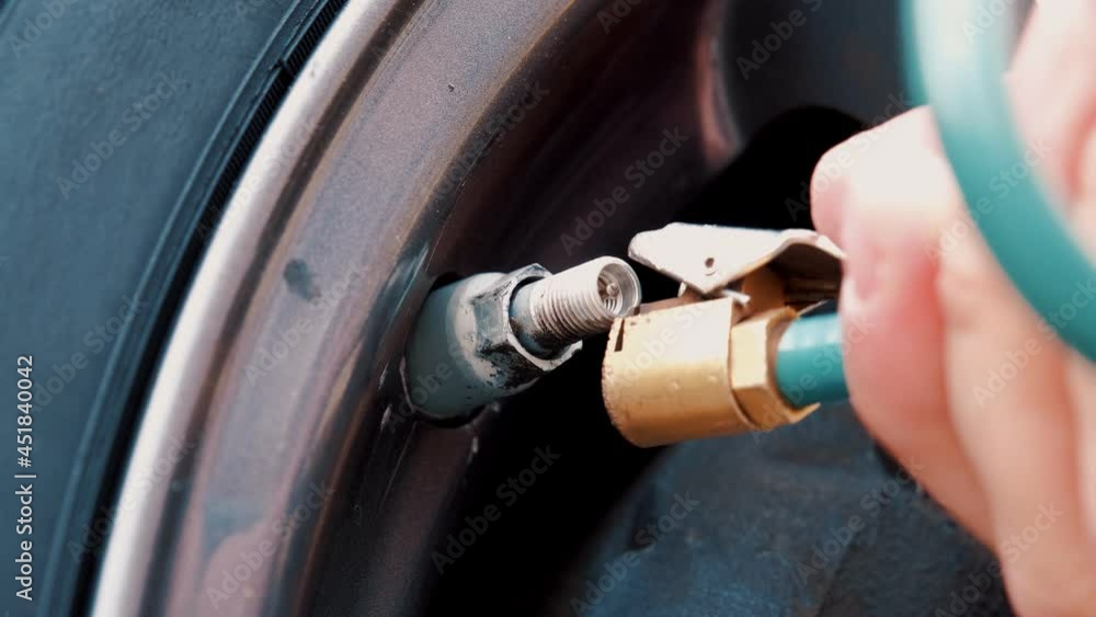 Caucasian Male Using Gas Station Compressor To Pump Car Tire Caucasian Male Using Gas Station Compressor To Pump Car Tire