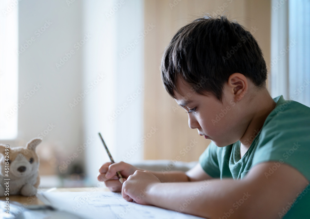 Schoolboy using pencil drawing on white paper sheet, Young kid doing school homework, Happy mixed race child enjoy doing arts and crafts at home on weekend. Home Education Schoolboy using pencil drawing on white paper sheet, Young kid doing school homework, Happy mixed race child enjoy doing arts and crafts at home on weekend. Home Education