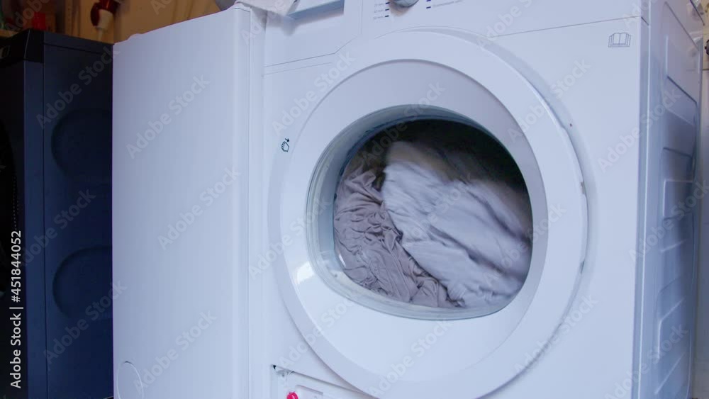 Washing machine or dryer with grey bed linen. Clothes are being washed in laundry. Close up view Washing machine or dryer with grey bed linen. Clothes are being washed in laundry. Close up view
