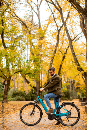 Young man with electric bicycle in the autumn park