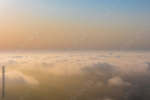 Colorful aerial sunset view over the cloud facing the sun. Scenic view above the clouds