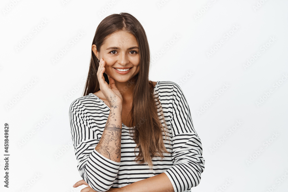 Adult woman smiling, touching her face and looking happy, posing against white background Adult woman smiling, touching her face and looking happy, posing against white background