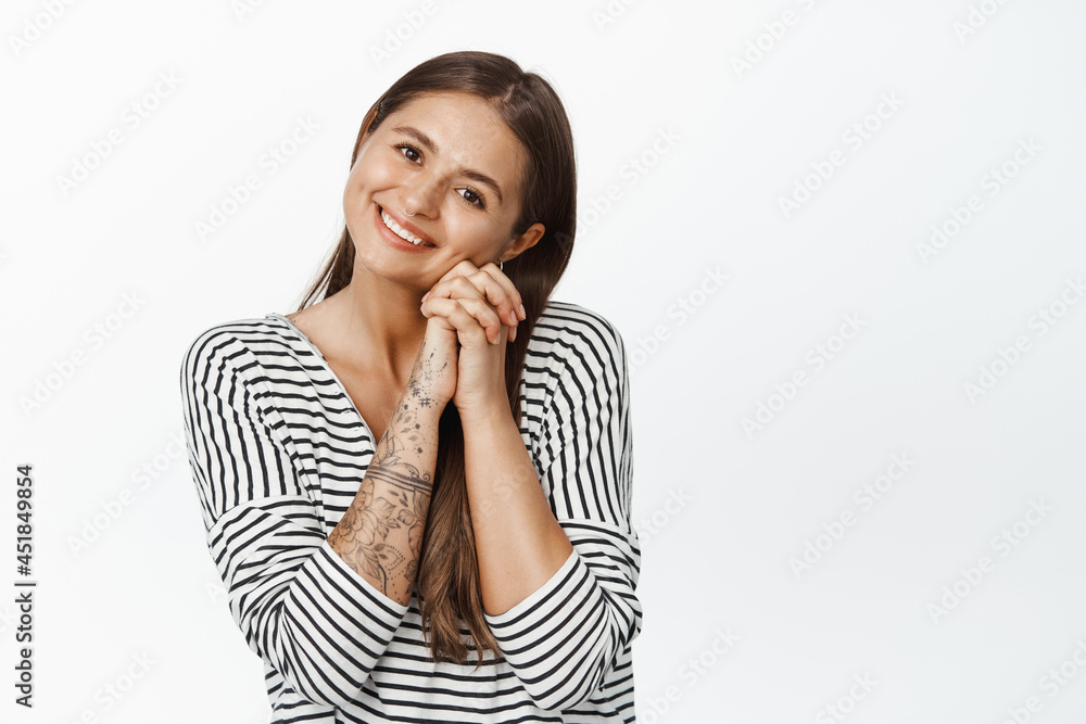 Image of cute and tender woman contemplating smth beautiful, lean on hands, smiling and gazing at camera, watching something adorable, white background Image of cute and tender woman contemplating smth beautiful, lean on hands, smiling and gazing at camera, watching something adorable, white background