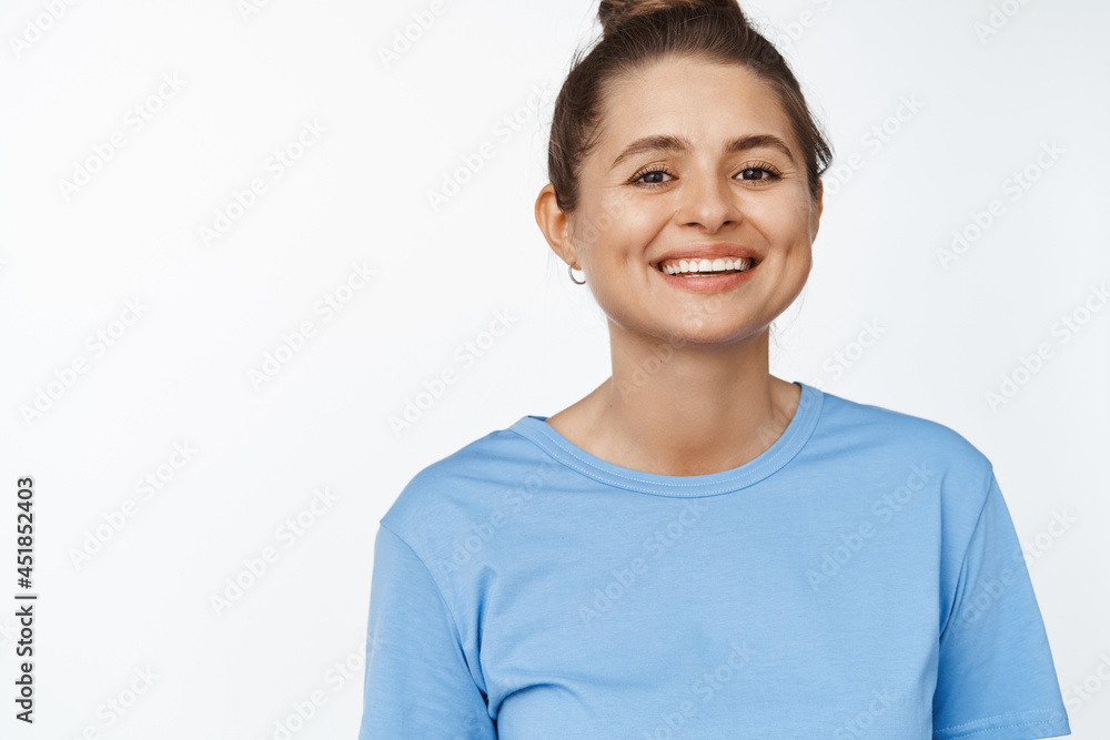 Portrait of young happy woman smiling at camera, wearing blue tshirt, white background Portrait of young happy woman smiling at camera, wearing blue tshirt, white background