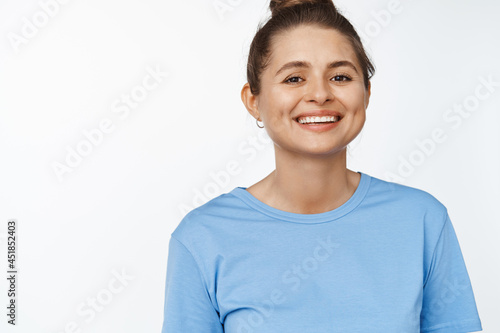 Portrait of young happy woman smiling at camera, wearing blue tshirt, white background