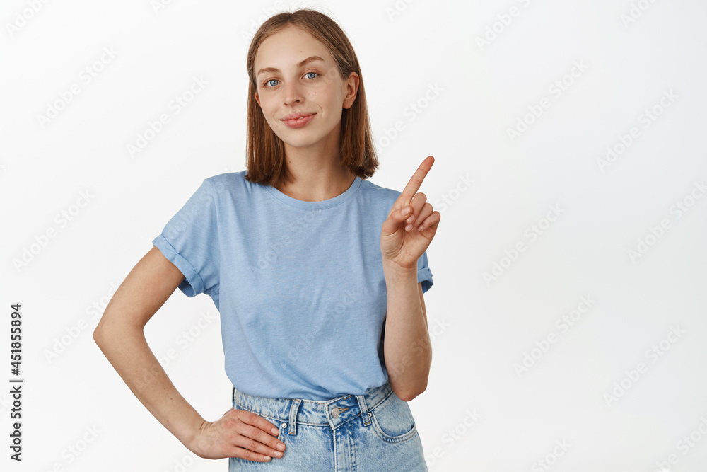Not so fast. Smiling beautiful teen girl with blond hair and blue eyes, shaking finger, pointing at smth, teach lesson, tell rule, standing against white background Not so fast. Smiling beautiful teen girl with blond hair and blue eyes, shaking finger, pointing at smth, teach lesson, tell rule, standing against white background