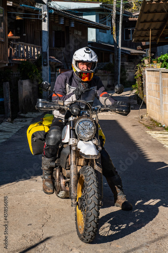 man stopping on road with his motorcycle in Thai village photo