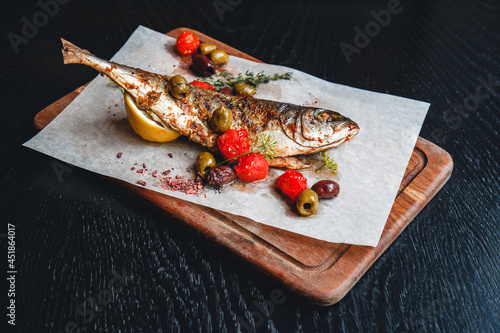Grilled fish with tomatoes, olives and lemon © Anastasia Prisunko
