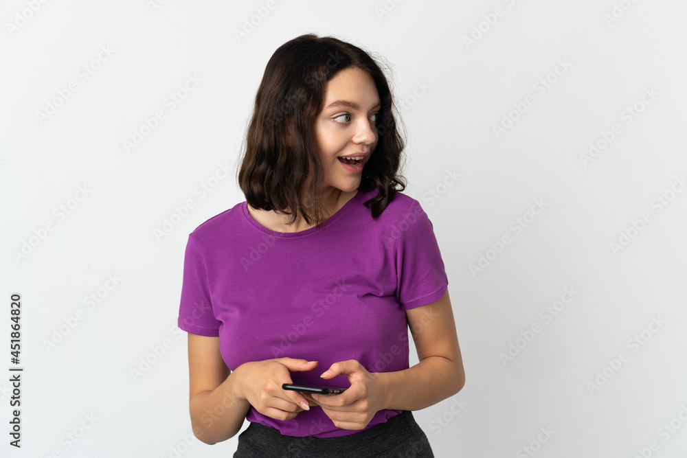 Teenager Ukrainian girl isolated on white background using mobile phone and looking up Teenager Ukrainian girl isolated on white background using mobile phone and looking up