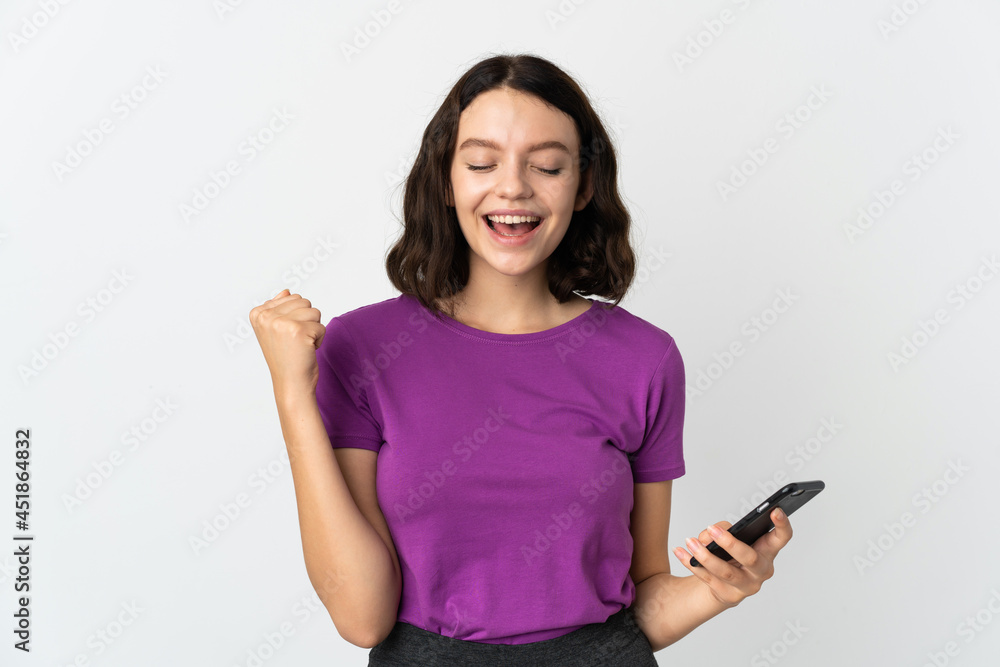 Teenager Ukrainian girl isolated on white background using mobile phone and doing victory gesture Teenager Ukrainian girl isolated on white background using mobile phone and doing victory gesture