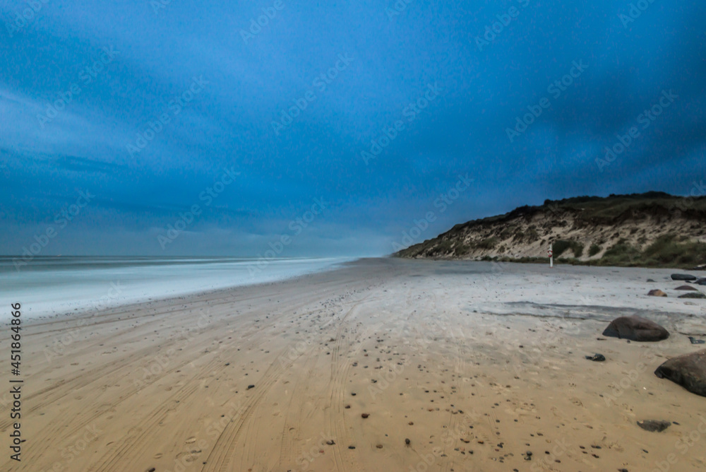 Long exposure photo of clouds rolling over a sand beach. Long exposure photo of clouds rolling over a sand beach.