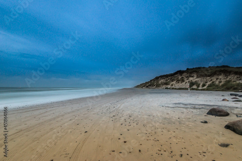 Long exposure photo of clouds rolling over a sand beach.