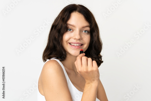 Teenager Ukrainian girl isolated on white background holding red lipstick
