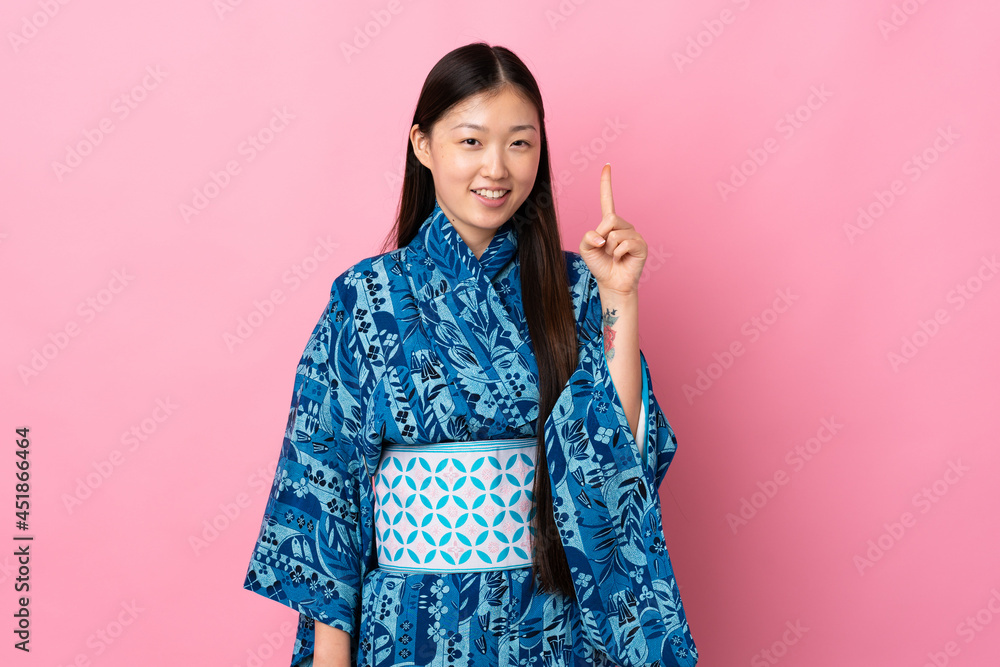 Young Chinese girl wearing kimono over isolated background pointing up a great idea Young Chinese girl wearing kimono over isolated background pointing up a great idea