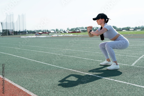 A Thai girl in a gray suit squats at the stadium and looks with a purposeful look photo