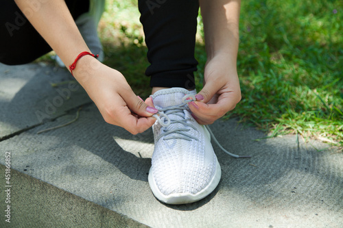  Woman runner tying her sneakers shoes. Outdoors.