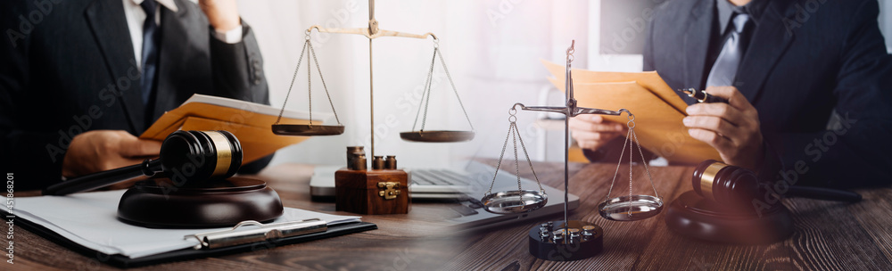 Business and lawyers discussing contract papers with brass scale on desk in office. Law, legal services, advice, justice and law concept picture with film grain effect Business and lawyers discussing contract papers with brass scale on desk in office. Law, legal services, advice, justice and law concept picture with film grain effect