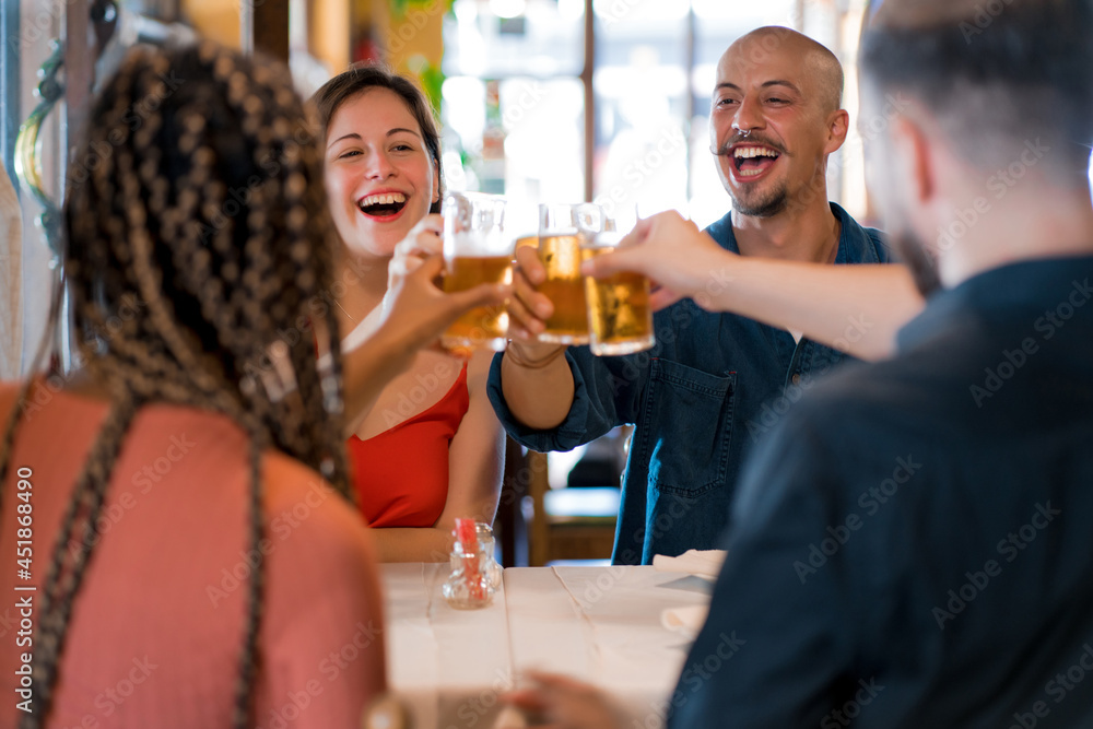 Group of friends toasting with beer glasses at a restaurant. Group of friends toasting with beer glasses at a restaurant.