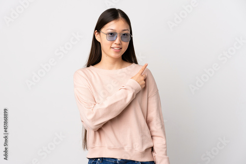 Young Chinese girl over isolated white background pointing to the side to present a product