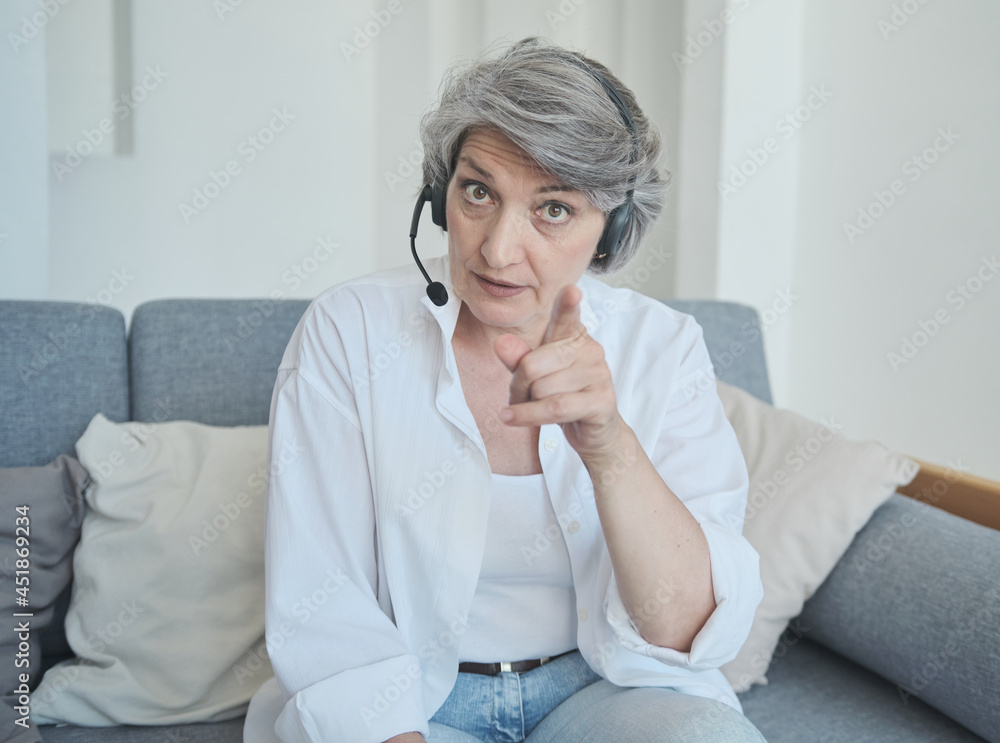 Senior female in headset streaming online in a social network and communicates with her subscribers, recording an educational video, chatting video call with kids, secretary work at home. Senior female in headset streaming online in a social network and communicates with her subscribers, recording an educational video, chatting video call with kids, secretary work at home.