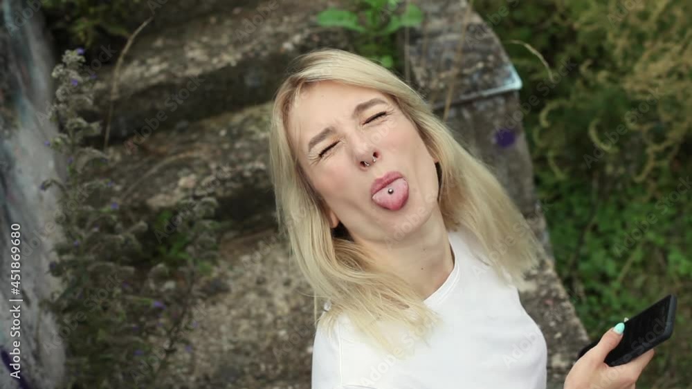 Beautiful blonde looks into her cell phone. Hipster girl sits on concrete steps outdoors and reads a messenger. View from above Beautiful blonde looks into her cell phone. Hipster girl sits on concrete steps outdoors and reads a messenger. View from above