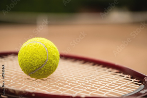 Close-up of a bright yellow tennis ball lies on a tennis racket.