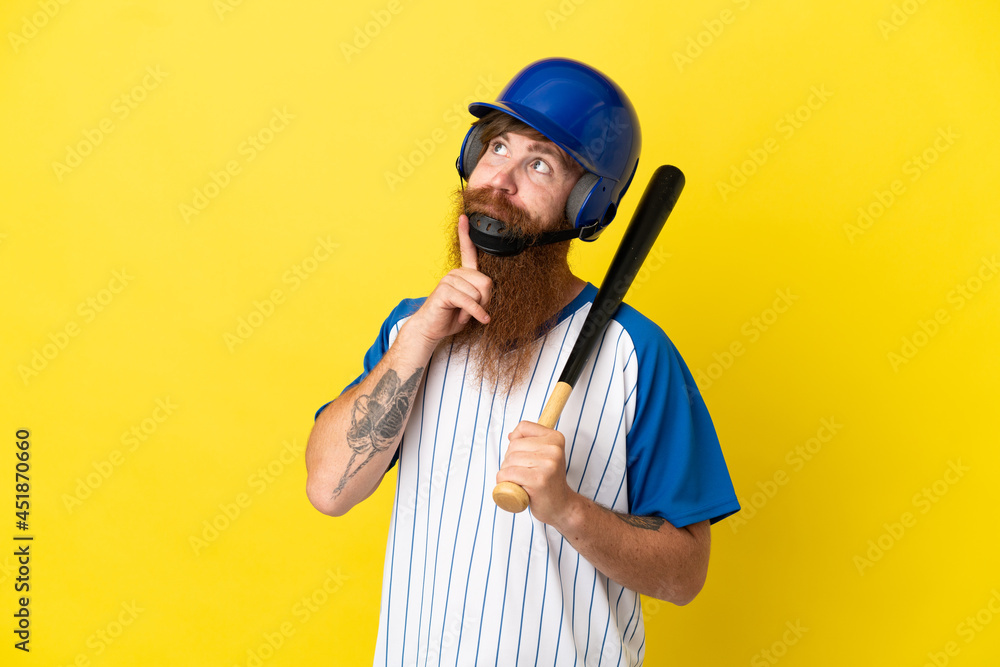 Redhead baseball player man with helmet and bat isolated on yellow background looking up while smiling