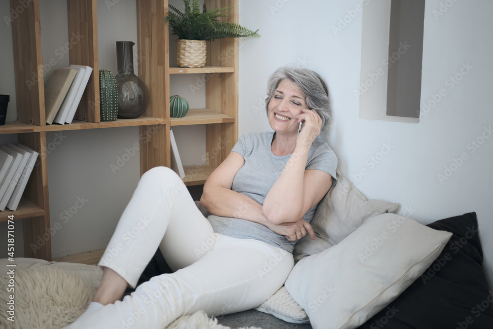 Senior mature old woman talks on the phone with friends or colleagues, relaxes, enjoys remote communication. Chat with children and grandkids, meeting on bed at home, social distance Senior mature old woman talks on the phone with friends or colleagues, relaxes, enjoys remote communication. Chat with children and grandkids, meeting on bed at home, social distance