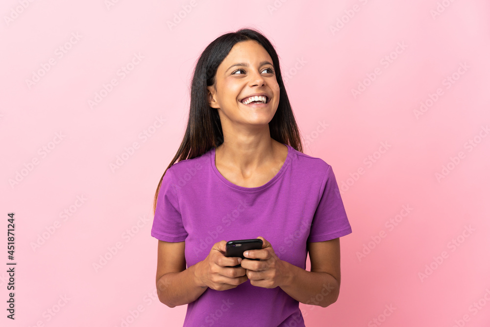 Caucasian girl isolated on pink background using mobile phone and looking up Caucasian girl isolated on pink background using mobile phone and looking up