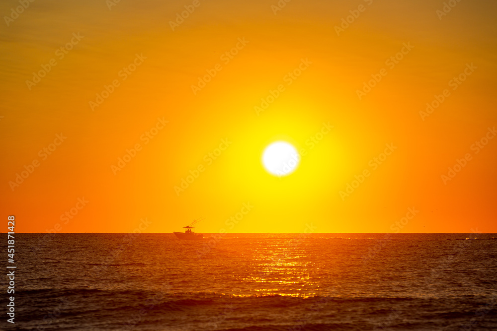 A fishing boat out on the ocean at sunrise 