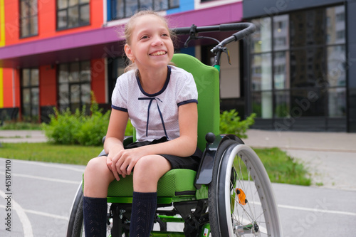 Special child on wheelchair. Girl in school uniform on the background of the school.