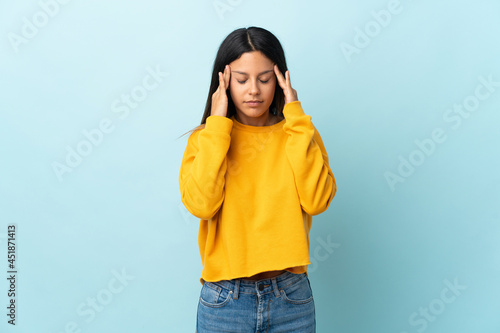 Caucasian girl isolated on blue background with headache © luismolinero