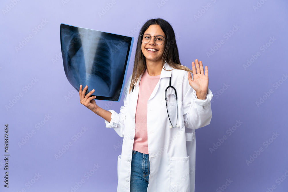 Young doctor woman holding a radiography saluting with hand with happy expression Young doctor woman holding a radiography saluting with hand with happy expression