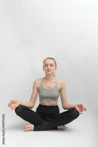Sukhasana. Easy Pose. Young slender woman does yoga and meditates. Girl practices pranayama.