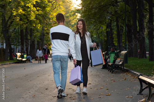 Guy and girl with shopping bags in their hands go to meeting and look at each other photo