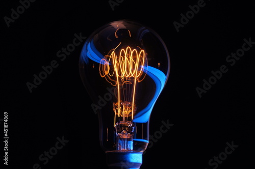 Classic vintage carbon filament edison lightbulb with accented colour across the glass. Concept or theme of idea, inspiration, \