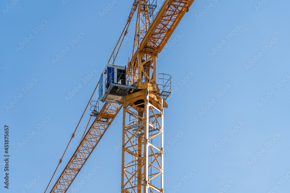 Yellow tower construction crane against blue sky background