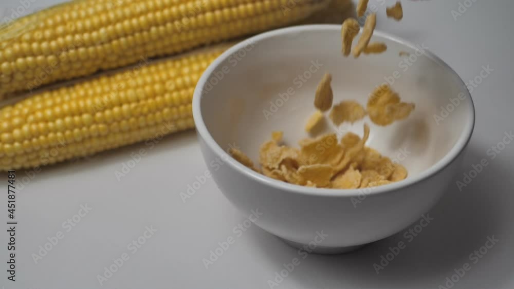 corn flakes fall into a bowl. corn cobs lie nearby. The concept of a healthy lifestyle, clean nutrition, diet. Breakfast. Slow motion. corn flakes fall into a bowl. corn cobs lie nearby. The concept of a healthy lifestyle, clean nutrition, diet. Breakfast. Slow motion.