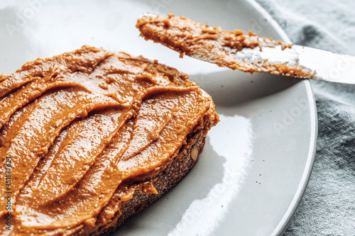 Close-up of peanut butter on toasted bread on a plate.