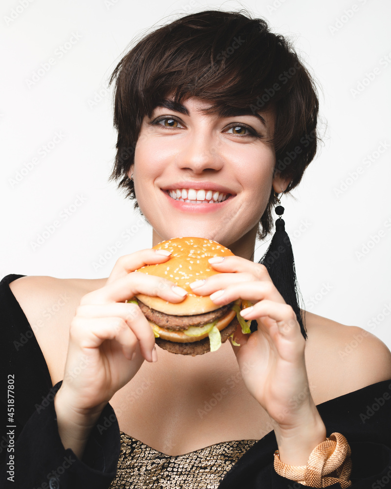 Fashionable portrait of an attractive white Caucasian girl with a burger in her hands Fashionable portrait of an attractive white Caucasian girl with a burger in her hands