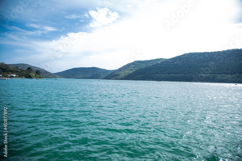 A lake with blue water, mountains are visible in the distance. Lake Abrau