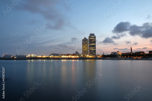 Barcelona, ​​views of the sea and the mapfre tower. seafront skyscrapers illuminated at sunset barcelona, ​​catalonia, spain