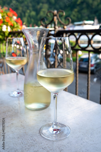 Tasting of white quality riesling wine served on outdoor terrace in Mosel wine region and old German town on background  Germany