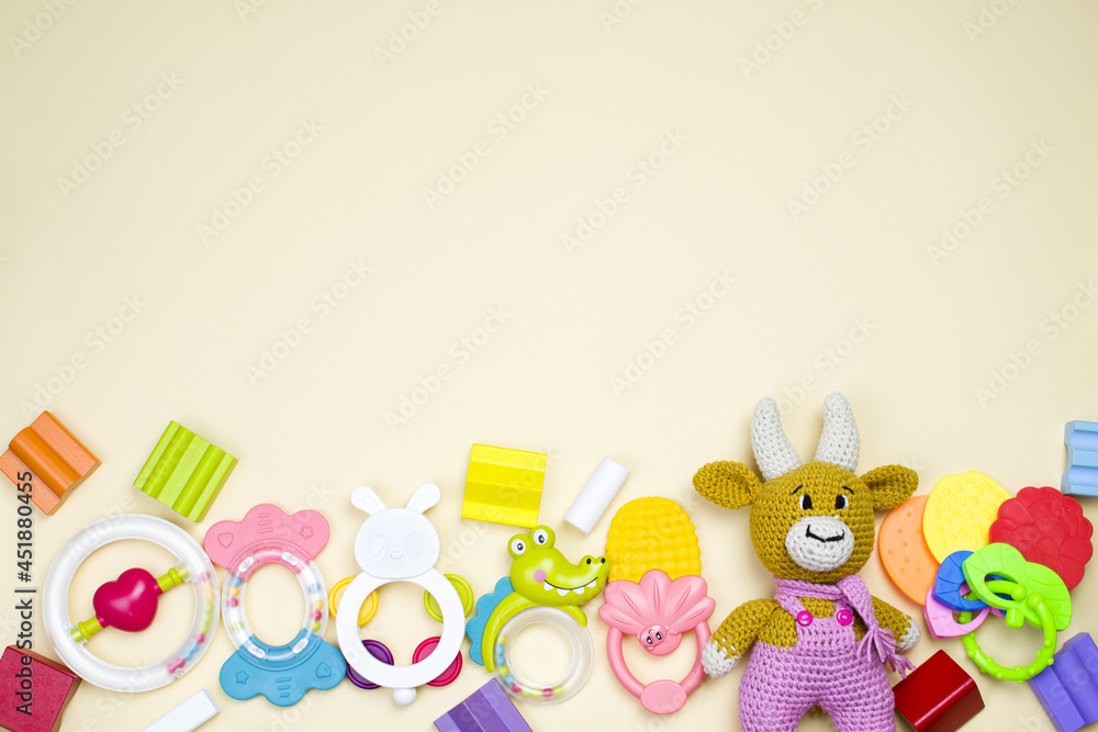 Obraz premium A lot of children's multi-colored toys are scattered on a beige background. The concept of a child's play. Background from toys. Top view, copy space.