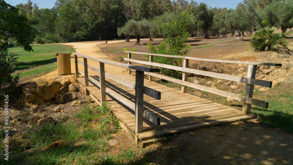 Small wooden bridge and dirt road in the Riberas del Guadaira park in Alcala de Guadaira (Seville, Spain). Public park with large grassy areas and space for outdoor exercise. 