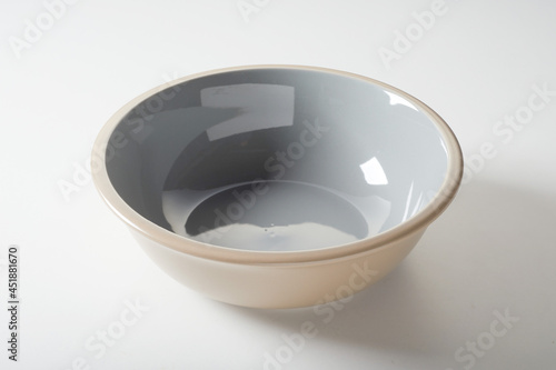 New empty beige ceramic bowl with shiny enamel on white background