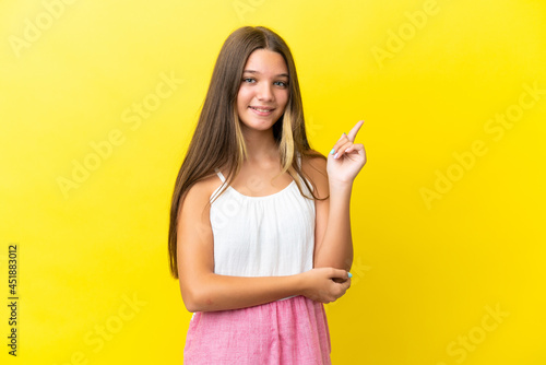 Little caucasian girl isolated on yellow background happy and pointing up
